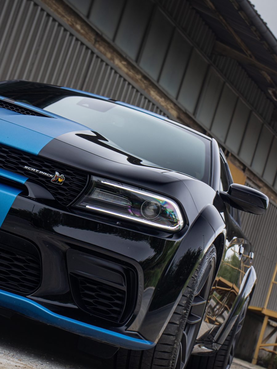 Zdjęcie czarnego Dodge Chargera Scat Pack Widebody z niebieskim pasem, ujęcie przodu pod kątem - fotografia przesłana przez klienta